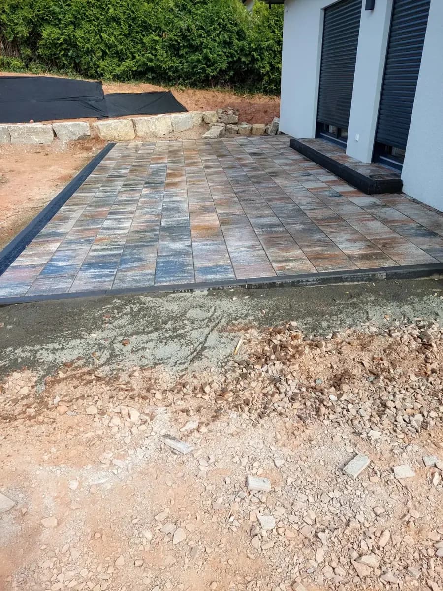 Nachher: fertig gepflasterte Terrasse mit großformatigen Betonplatten in Muschelkalk-Optik am Neubau
